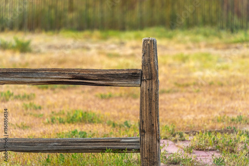 A old wooden rail fence with texture and a background of dry grass