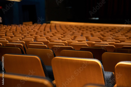 Empty auditorium interior with rows of orange velvet seats facing stage in theater