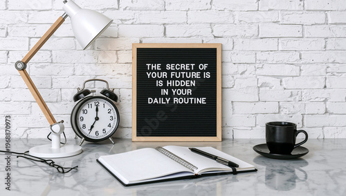 A well-organized modern desk setup featuring a motivational letter board, an alarm clock, and an open notebook, inspiring focus and productivity for daily routines.