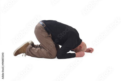 side view of a man on his knees in despair with his head on the ground
