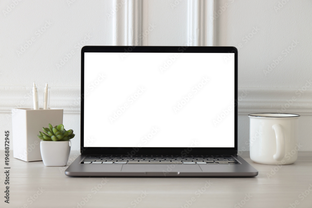 Fototapeta premium Stylish workplace. Laptop with blank screen, cup of drink, houseplant and decor on white wooden table