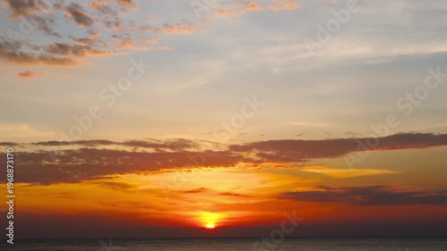 Dramatic ocean sunset with vibrant colors and cloudy sky over calm sea