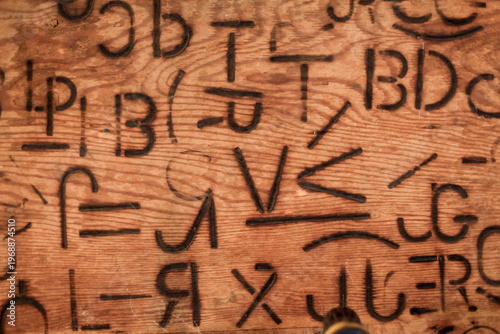 Cattle branding symbols burned into wood, western ranch heritage and livestock marks