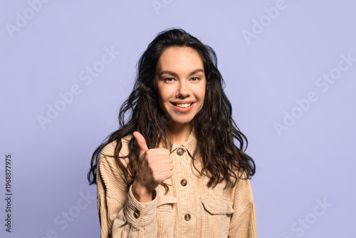 Photography A person stands with a light purple background and gives a thumbs up