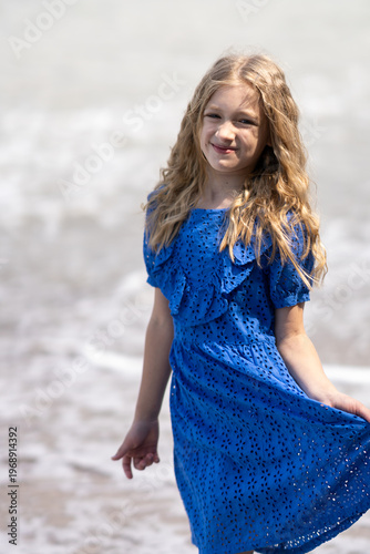 A little girl walks along the beach along the ocean