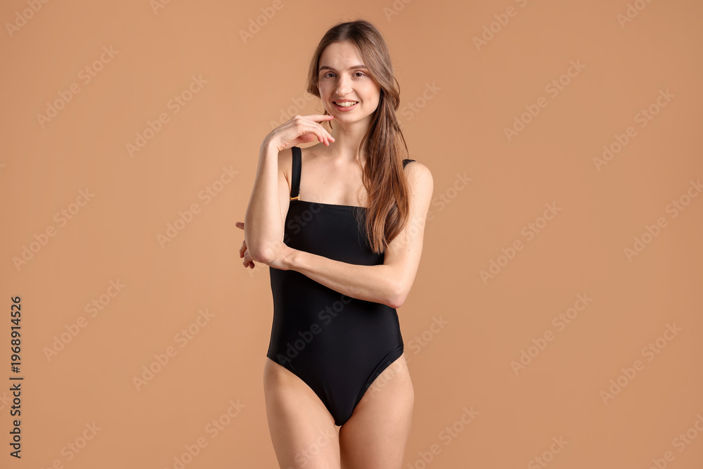 Obraz premium Beautiful woman in stylish swimsuit posing on brown background