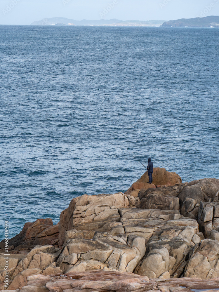 © dreakrawi - Rückansicht eines einzigen Anglers auf den Felsen von La Coruna © dreakrawi - Rückansicht eines einzigen Anglers auf den Felsen von La Coruna