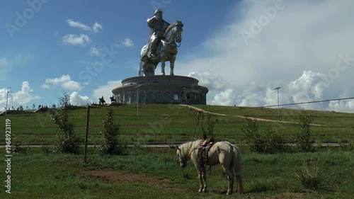 Ulaanbaatar, Mongolia - July 31, 2015: Huge monument to Genghis Khan in Mongolia on background of cloudy sky.  Horse grazing in front of the monument.