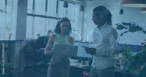 A group of businesspeople are discussing work while using laptops in a modern office