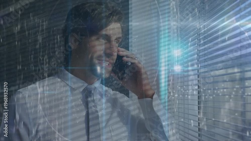 A young caucasian male is talking on a mobile phone in a modern office