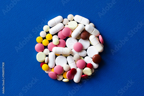 Pills and capsules are arranged in a circle in the center of the photo. Close-up. Medical drugs and treatment with pills