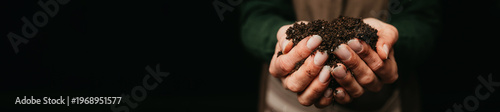 Closeup Hands Holding Rich Soil over dark background.
