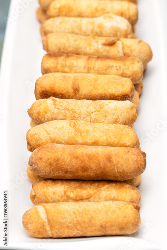 Delicious cheese-filled tequeños served on a long white plate, traditional Venezuelan food