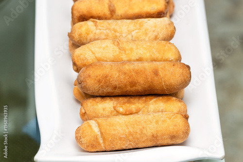Delicious cheese-filled tequeños served on a long white plate, traditional Venezuelan food