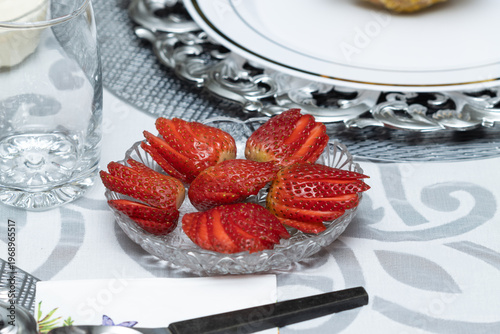 Sliced strawberries served on a clear glass plate, fresh fruit close-up