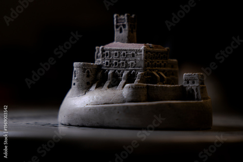 Miniature medieval castle model close up with dramatic lighting and dark background