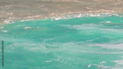 Aquamarine river currents twist and churn in Los Alerces National Park, Patagonia, Argentina. The water meets the shore, creating an ethereal display of nature's power.