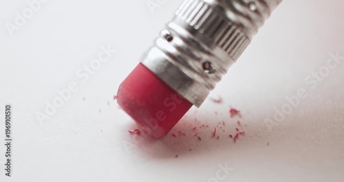 Closeup of pink pencil eraser erasing and creating a mess on white paper. Conceptual bad idea, fixing problems, failure or mistake, wrong decision, or to remove an error. Back to School supplies.
