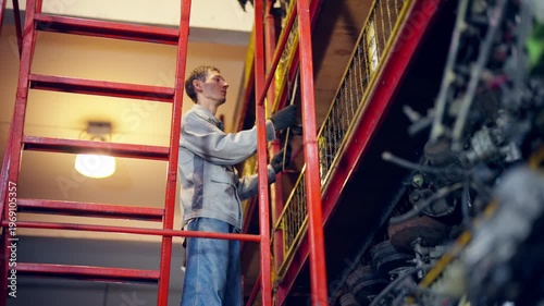 Auto mechanic selecting spare parts from storage shelves in industrial workshop, vehicle maintenance repair process in garage, engineering workflow inventory inspection in automotive service facility.