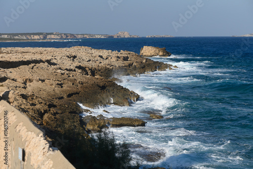 Waves crashing against rugged coastline during a sunny afternoon at the serene seaside.