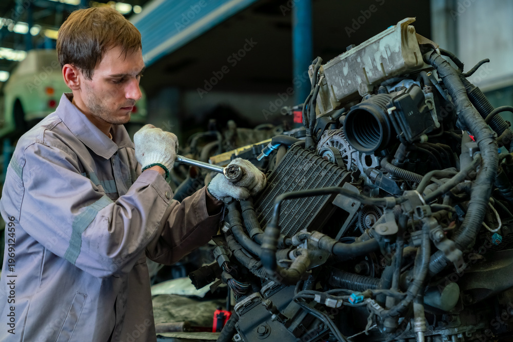 Fototapeta premium Male mechanic repairing used car engine parts in industrial garage workshop, automotive engineering inspection and maintenance service car repair shop, technician working on mechanical system factory