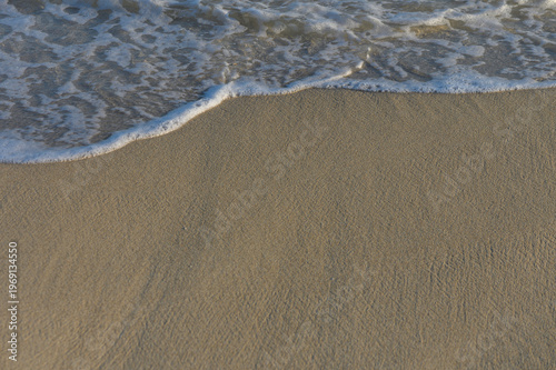 Gentle waves dancing on golden sand during a serene sunset on a tranquil beach.