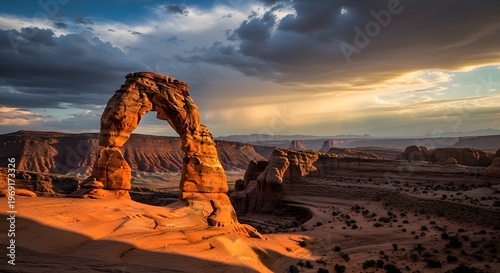 Majestic natural rock arch standing against a dramatic sunset sky with sweeping clouds and golden light over a canyon landscape
