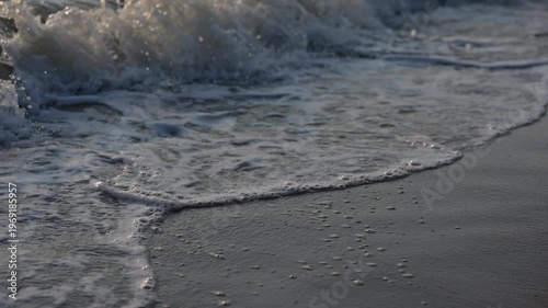 Gentle ocean waves washing over a sandy beach shoreline