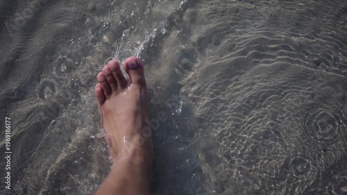Person walking barefoot on a sandy beach shore