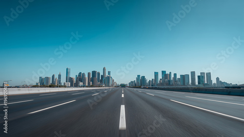 Wide highway road with city skyline and clear blue sky buildings