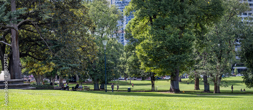 Slika na platnu Panoramic view of Flagstaff Gardens in Melbourne, Australia, featuring expansive green lawns, mature trees, and people enjoying leisure activities