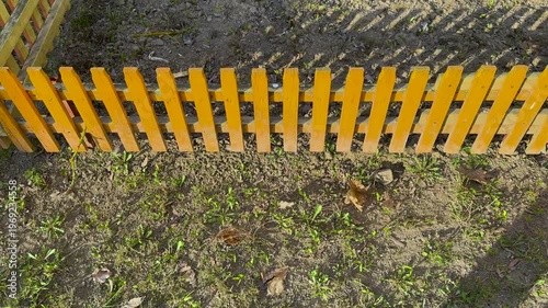 Wooden fence seen from above in a garden with soil and small plants during daytime