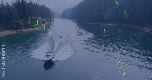 Foto Cruising tow boat, waterskier wearing PFD cutting across forest lake forming wak
