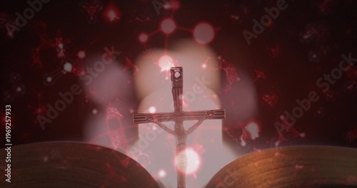 Silhouetting metal crucifix with corpus standing upright at altar, with open book and bokeh lights