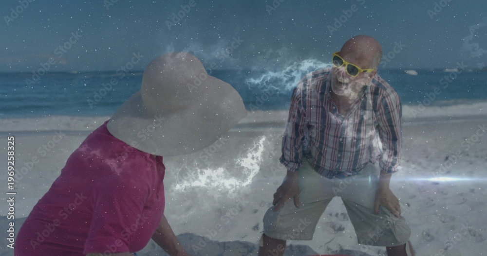 Obraz premium Leaning senior couple smiling at beach, wearing pink top, sunhat, plaid shirt, nebula overlay