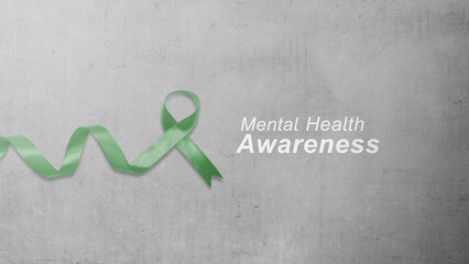 A minimalist composition featuring a green awareness ribbon and the text 'Mental Health Awareness' set against a textured gray concrete wall background