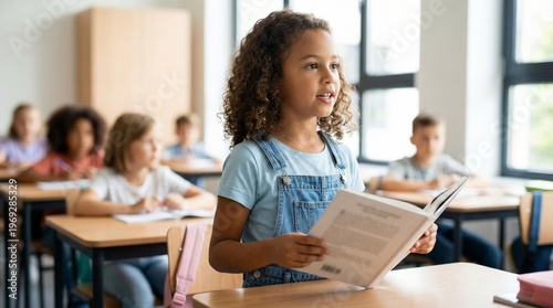 Young girl reading book aloud in classroom with attentive classmates  