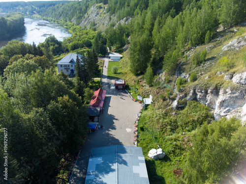 High-angle drone shot of the Kungur Ice Cave (Kungurskaya Ledyanaya Peshchera) entrance area and tourist complex in the Perm Krai region, near the town of Kungur, Russia. The image captures the iconic
