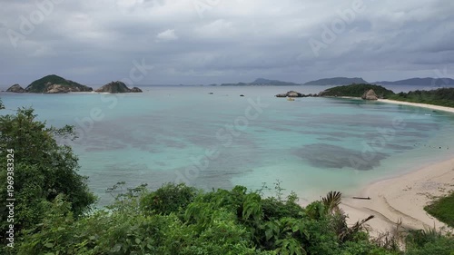 渡嘉敷島・阿波連漁港を見下ろす風景 曇天でも輝くエメラルドグリーンの海とハナリ島 動画素材 4K