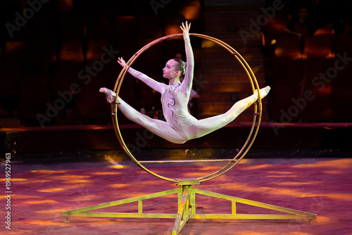 A teenage girl performs an acrobatic act on a circus ring. Concept is that children are involved in sports and circus arts