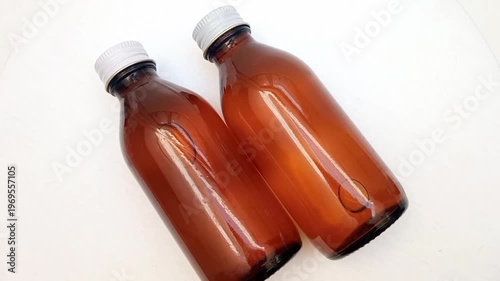 Amber glass bottles with cap rotating on white background, brown glass bottles for pharmaceuticals, syrups, essential oils, and cosmetics