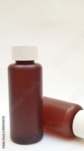 Amber plastic bottles with cap rotating on white background, brown plastic bottles for pharmaceuticals, syrups, essential oils, and cosmetics, vertical clip