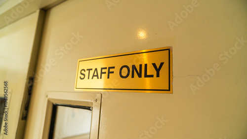 Принти на полотні a close-up photograph of a metallic gold-colored sign that reads staff only, mounted on a clean cream door to indicate restricted access for authorized personnel within a professional building