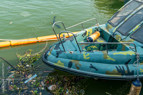 Fotografie Camouflage boat floats in murky green water