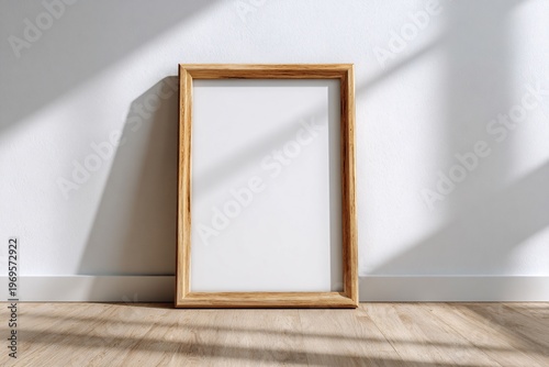 Empty wooden picture frame leaning against a white wall