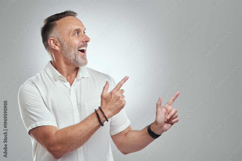 Fototapeta premium Mature, happy man and pointing with space in studio for advertising on a white background. Male person, model or showing with smile for option, choice or selection on mockup for marketing or tips