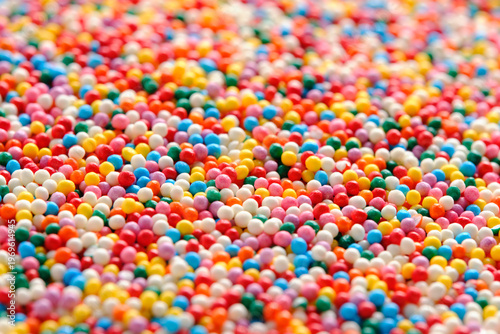 High angle horizontal view dense pile of multi colored nonpareil sugar beads creating joyful texture.