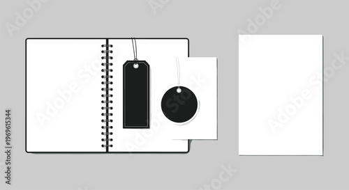 Office and stationary branding mock up featuring an open spiral notebook with black price tags and a blank white piece of paper for design.