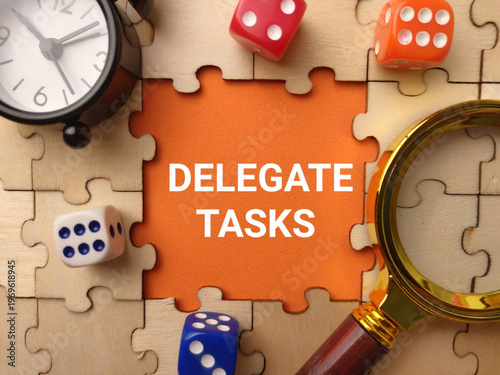 A conceptual flat lay photo featuring the text DELEGATE TASKS on a vibrant orange center piece