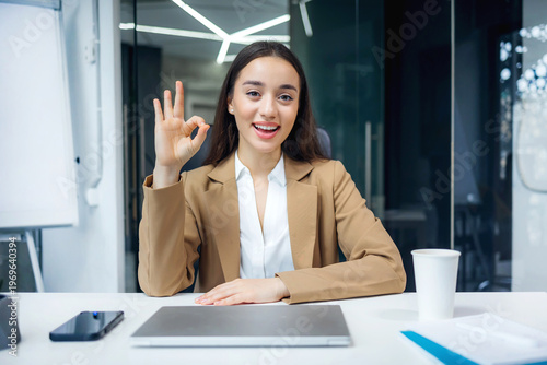 Foto happy and successful female programmer inside office at workplace show ok sign,